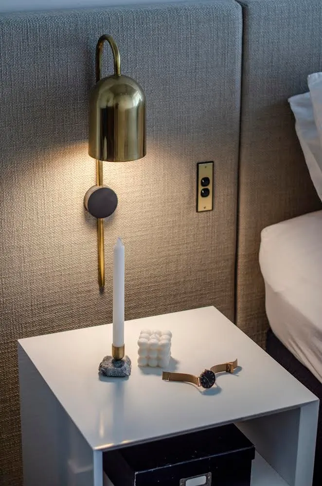 Brass wall light above a bedside table